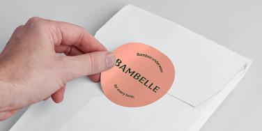 Hand putting a big pink round sticker on an envelope
